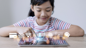 symbolisch für die Generation Alpha: ein kleines Mädchen verwendet ein Tablet, mehrere Piktogramm symbolisieren die Anwendungsvielfalt des Gerätes