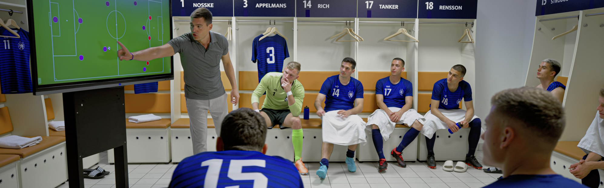 Ausbildung 25 Plus - im übertragenen Sinne - ein Fußballtrainer erklärt seiner Mannschaft in der Kabine die Spieltaktik